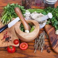 mortars, greens and dried spices on wooden table photo