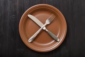vista superior del plato marrón con cubiertos en la mesa oscura foto