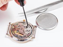repairer replaces battery in quartz watch close up photo