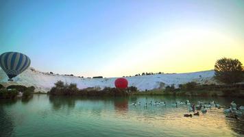 Globos aerostáticos de 8k volando en una zona turística como colinas nevadas junto al lago video