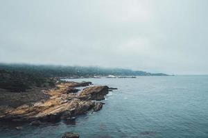 Mist over ocean bay with rock cliffs photo