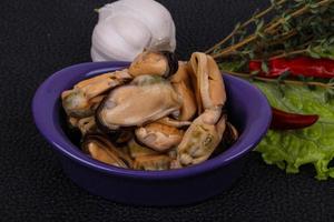 Pickled mussels in the bowl served pepper, garlic and salad photo