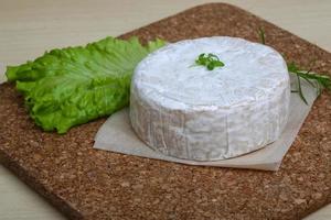 queso camembert sobre tabla de madera y fondo de madera foto