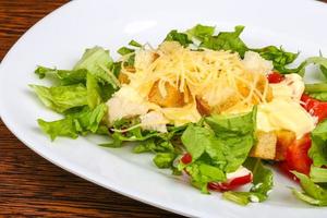 Caesar salad on the plate and wooden background photo