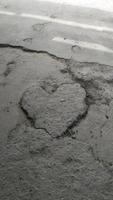 Stone heart on asphalt. Asphalt in the shape of a heart. Heart under your feet photo