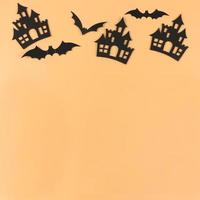 Top view decorations for Halloween holiday, castles and bats on orange background with copy space. photo