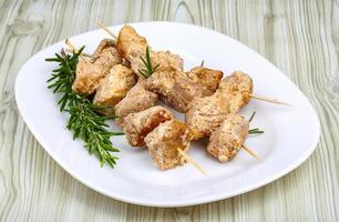 Chicken skewers on the plate and wooden background photo