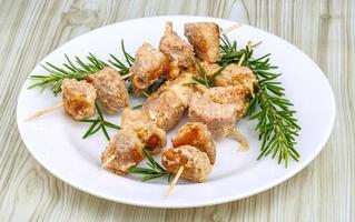 Chicken skewers on the plate and wooden background photo
