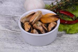 Pickled mussels in the bowl served pepper, garlic and salad photo