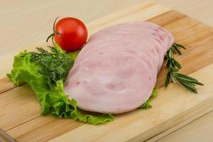 Sliced ham on wooden board and wooden background photo