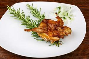 Grilled quail on the plate and wooden background photo