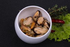 Pickled mussels in the bowl served pepper, garlic and salad photo