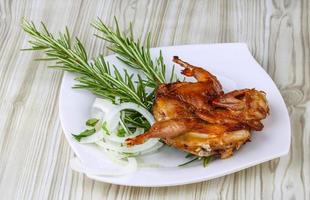 Grilled quail on the plate and wooden background photo