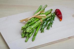 Raw asparagus on wooden board and wooden background photo