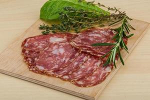 Salami on wooden board and wooden background photo