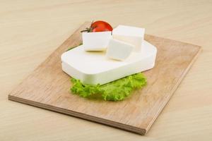 Feta cheese on wooden board and wooden background photo