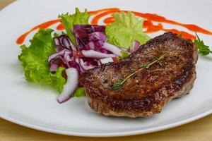 Beefsteak on the plate and wooden background photo