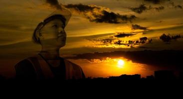 Silhouette double exposure image of architecture or civil engineer with orange sky sunset,builder wearing helmet,construction industry expand and grow,concept work in success. photo