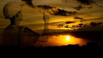 Silhouette double exposure image of architecture or civil engineer with orange sky sunset,builder wearing helmet,construction industry expand and grow,concept work in success. photo