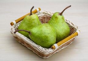 Green pears in a basket on wooden background photo