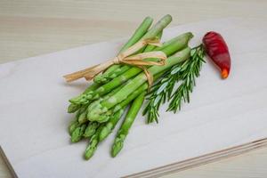 Raw asparagus on wooden board and wooden background photo