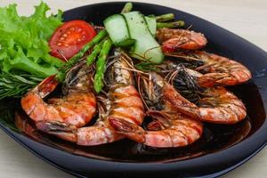 Grilled prawns on the plate and wooden background photo