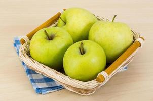 Green apple in a basket on wooden background photo