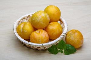 Yellow plums in a basket on wooden background photo