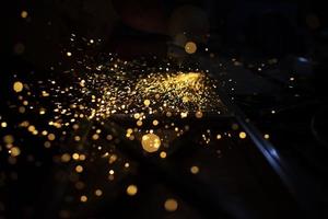 Sparks of yellow color. Metal treatment. Lights in dark. Sparks from split grinding disc. photo