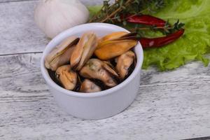 Pickled mussels in the bowl served pepper, garlic and salad photo