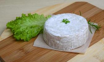 queso camembert sobre tabla de madera y fondo de madera foto