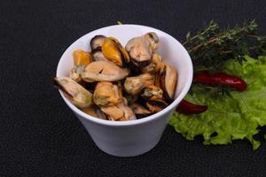 Pickled mussels in the bowl served pepper, garlic and salad photo