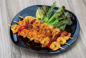 Prawn skewer on the plate and wooden background photo