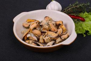 Pickled mussels in the bowl served pepper, garlic and salad photo