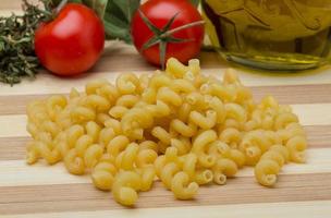 Cellentani pasta on wooden board and wooden background photo