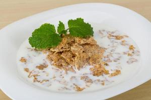 copos de maíz en el plato y fondo de madera foto