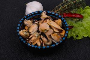 Pickled mussels in the bowl served pepper, garlic and salad photo