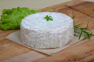 Camembert cheese on wooden board and wooden background photo