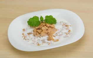 copos de maíz en el plato y fondo de madera foto