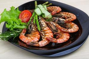 Grilled prawns on the plate and wooden background photo