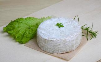 queso camembert sobre tabla de madera y fondo de madera foto