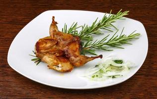 Grilled quail on the plate and wooden background photo