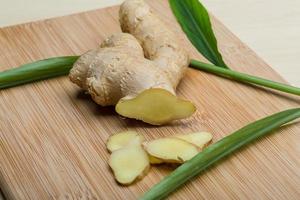 Ginger root on wooden board and wooden background photo