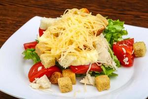 Caesar salad on the plate and wooden background photo