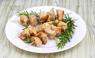Chicken skewers on the plate and wooden background photo