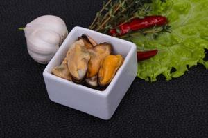 Pickled mussels in the bowl served pepper, garlic and salad photo