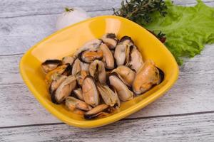 Pickled mussels in the bowl served pepper, garlic and salad photo