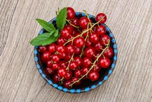 Red currants in a bowl on wooden background photo