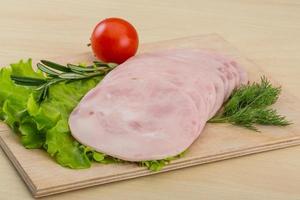 Sliced ham on wooden board and wooden background photo