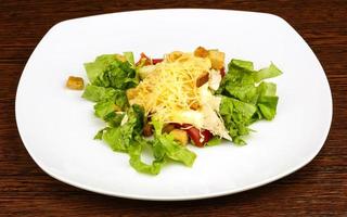 Caesar salad on the plate and wooden background photo